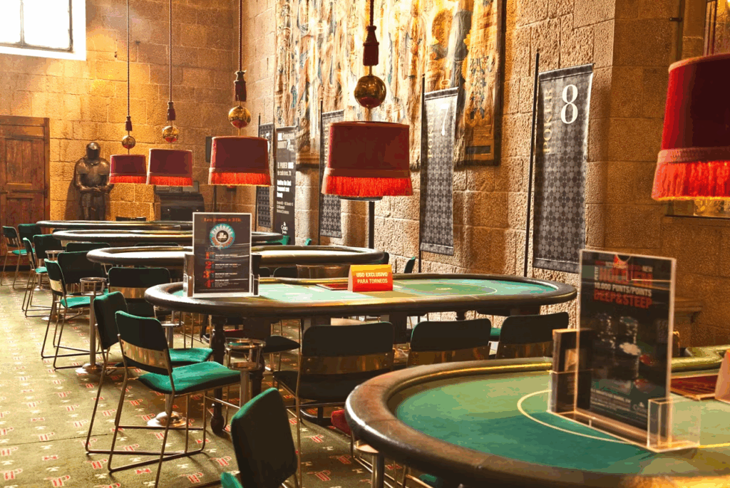 Sala de póker y máquinas tragaperras del Casino Peralada, con mesas iluminadas y ambiente elegante dentro del castillo.