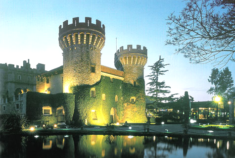 Fachada del Castell de Peralada iluminada al atardecer, con jardines y entrada principal del Casino Peralada.