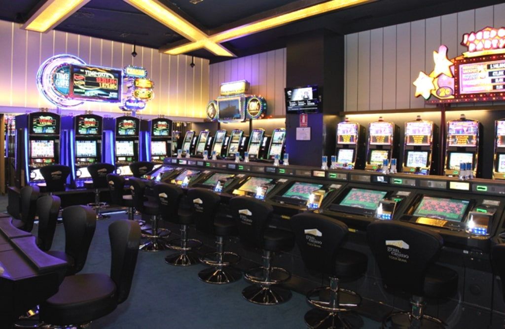 Sala de tragaperras del Gran Casino Costa Brava con máquinas de última generación y luces de neón.